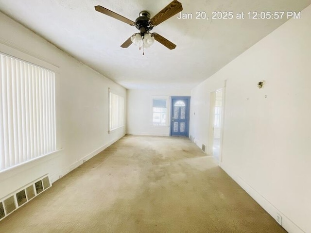 empty room featuring ceiling fan and light carpet