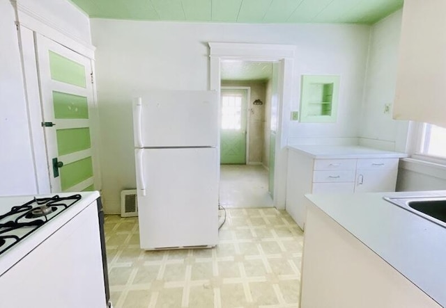 kitchen with white appliances, a wealth of natural light, and white cabinets