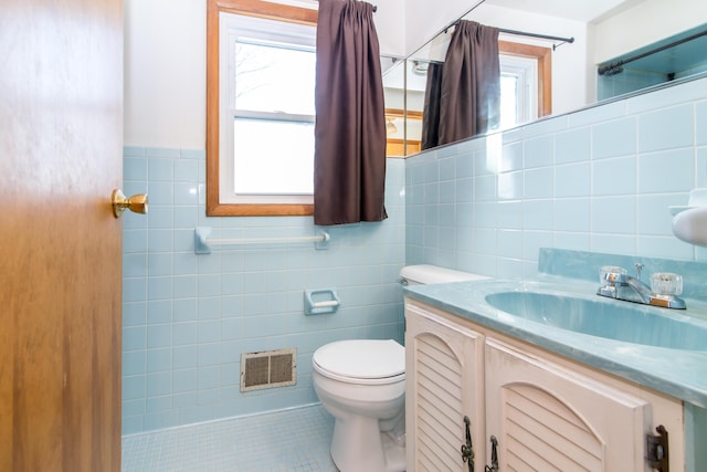 bathroom with tile patterned flooring, vanity, a healthy amount of sunlight, and tile walls