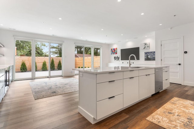 kitchen featuring sink, dishwasher, white cabinetry, dark hardwood / wood-style floors, and a center island with sink