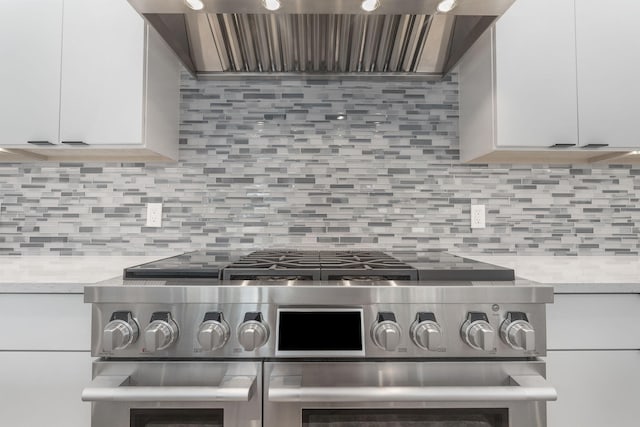 kitchen featuring tasteful backsplash, extractor fan, white cabinetry, and double oven range