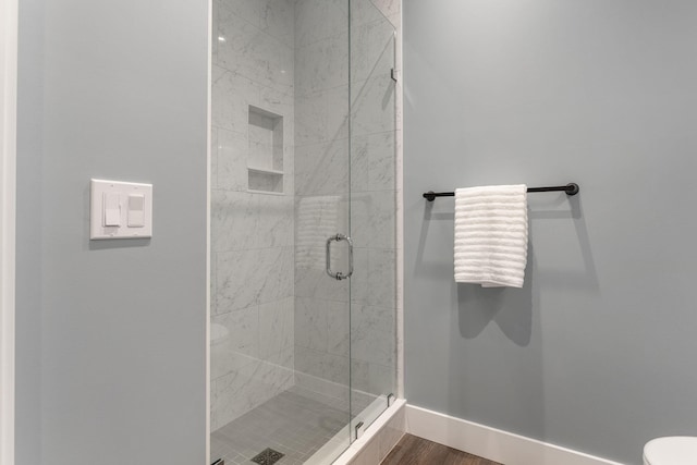 bathroom featuring hardwood / wood-style floors, an enclosed shower, and toilet