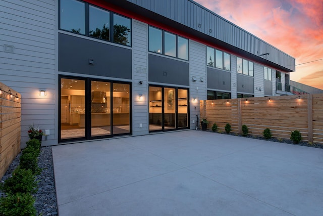 back house at dusk featuring a patio