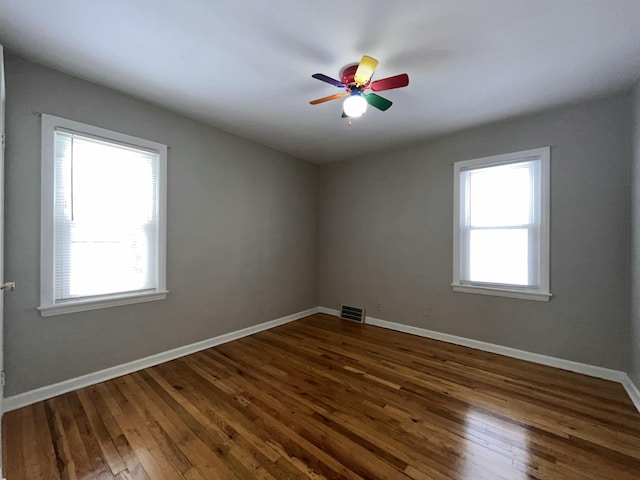 unfurnished room featuring dark hardwood / wood-style flooring, a wealth of natural light, and ceiling fan