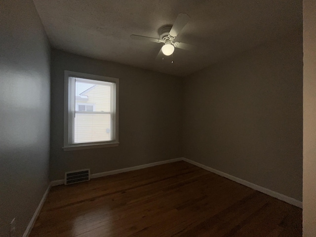 empty room with dark hardwood / wood-style flooring and ceiling fan