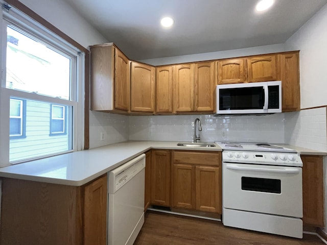 kitchen with dark wood-type flooring, white appliances, sink, and decorative backsplash