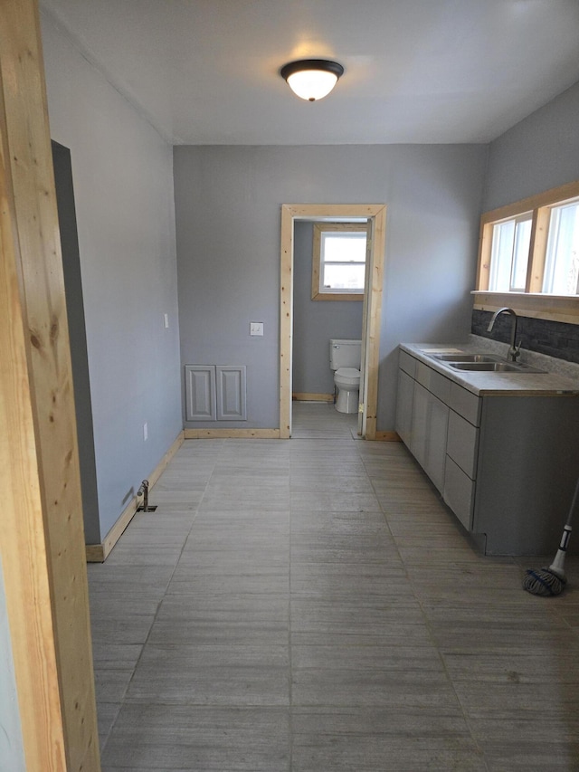 interior space with light countertops, a sink, baseboards, and modern cabinets