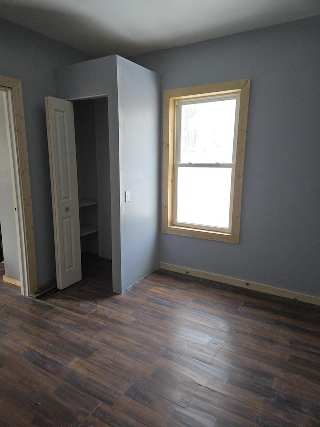 unfurnished bedroom with dark wood finished floors and baseboards