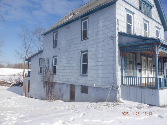 snow covered property with covered porch