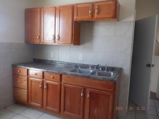 kitchen with light tile patterned flooring, sink, and tile walls