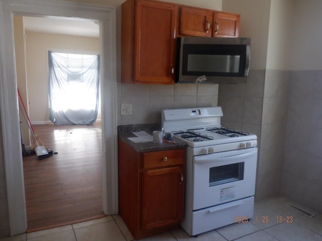 kitchen featuring tasteful backsplash, light tile patterned flooring, and white gas range