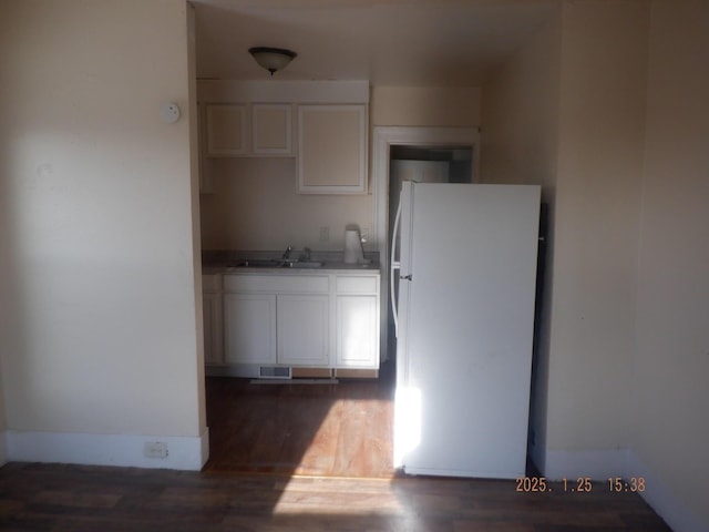 kitchen with sink, dark wood-type flooring, white cabinets, and white fridge