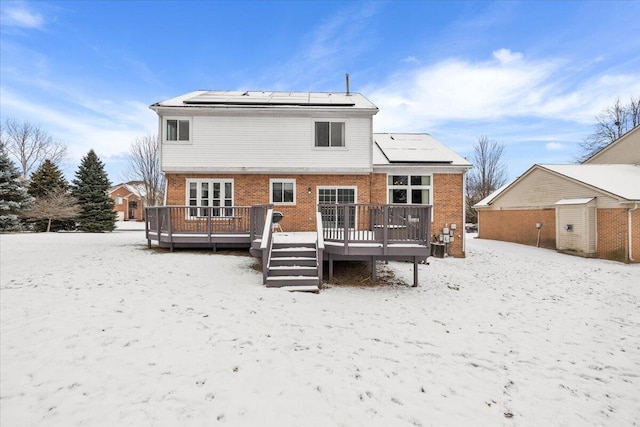 snow covered rear of property with a deck