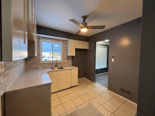 kitchen featuring backsplash, light tile patterned floors, sink, and white cabinets