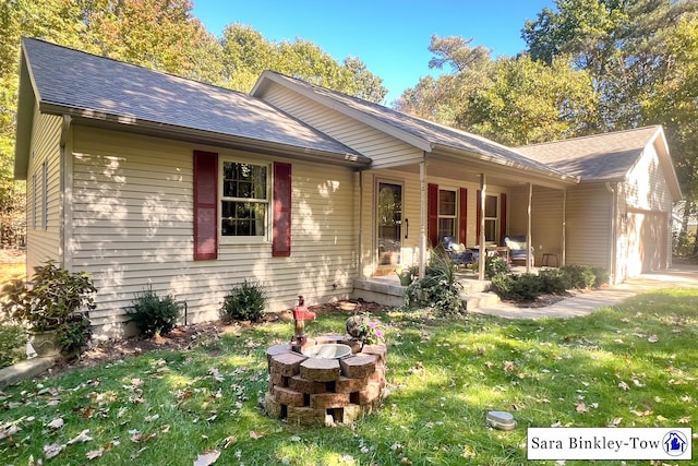 single story home featuring a garage, a front lawn, and a fire pit