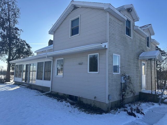 view of snow covered exterior featuring a sunroom