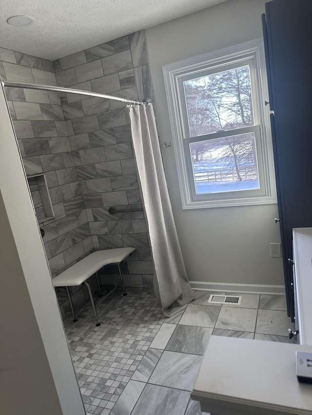 bathroom with curtained shower and a textured ceiling