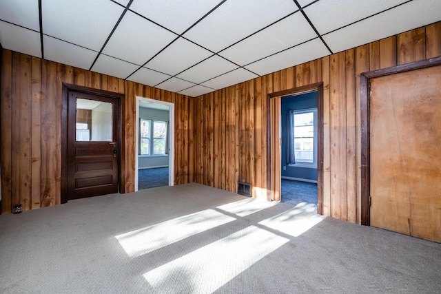 carpeted spare room featuring wooden walls