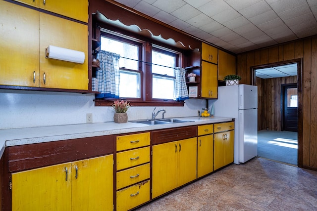 kitchen featuring sink, white fridge, and wood walls