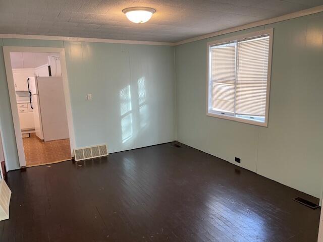 unfurnished room featuring ornamental molding and dark hardwood / wood-style flooring