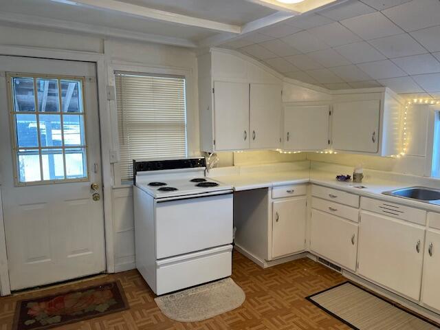 kitchen featuring parquet flooring, white range with electric cooktop, sink, and white cabinets