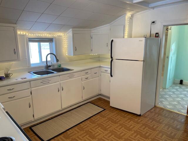 kitchen featuring white refrigerator, sink, and white cabinets