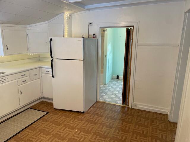 kitchen featuring light parquet floors, white cabinetry, and white fridge