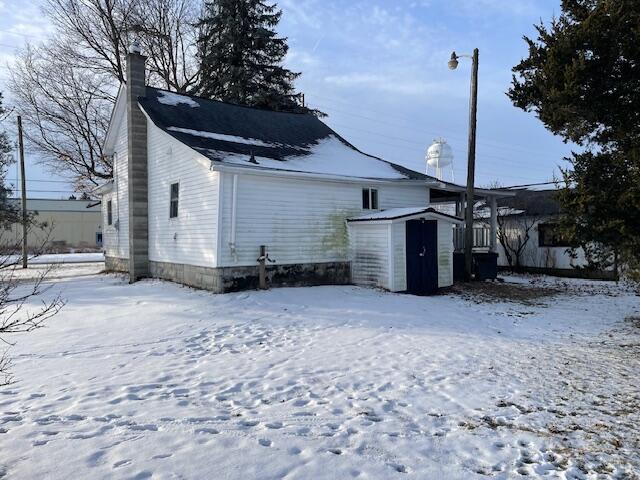 snow covered house featuring a storage shed