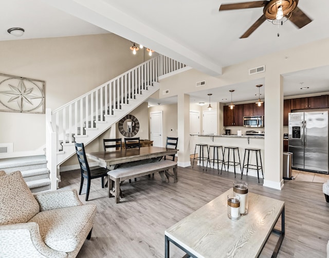 living room featuring beam ceiling, light hardwood / wood-style floors, and ceiling fan