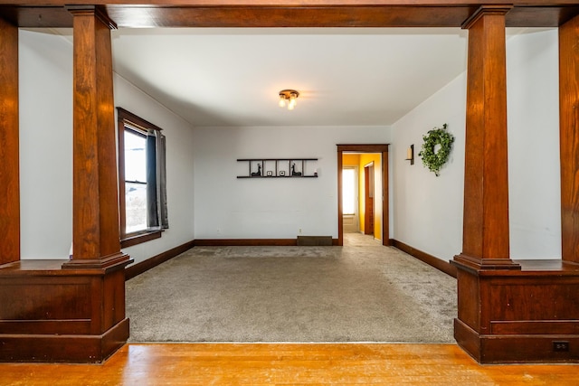 spare room featuring decorative columns and light colored carpet