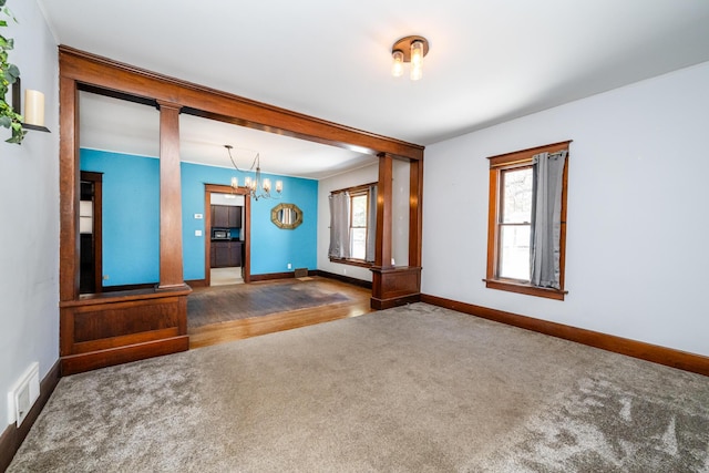 carpeted empty room with a notable chandelier