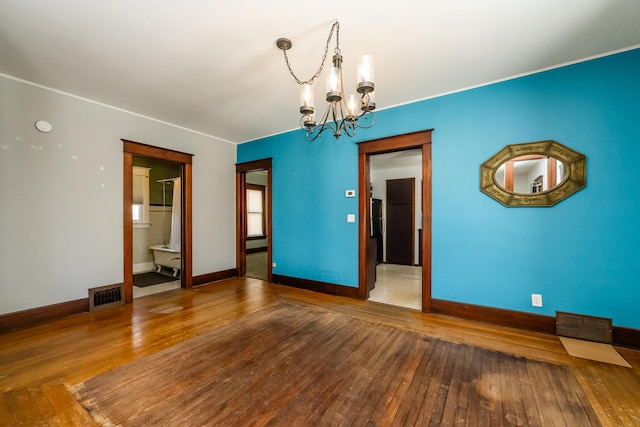 unfurnished room with hardwood / wood-style flooring and an inviting chandelier