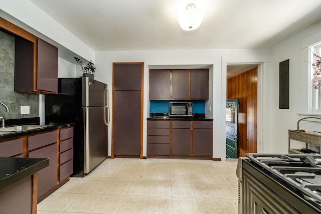 kitchen featuring tasteful backsplash, dark brown cabinets, sink, and stainless steel refrigerator