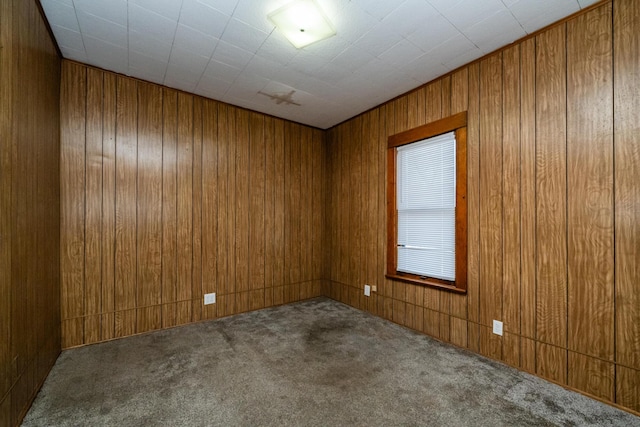 carpeted empty room with wood walls