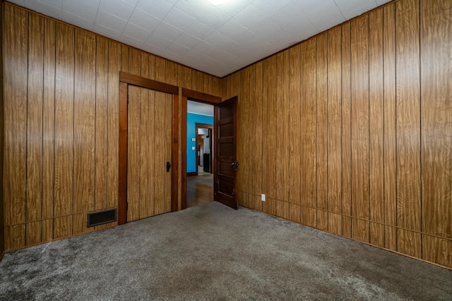 empty room with carpet floors and wood walls