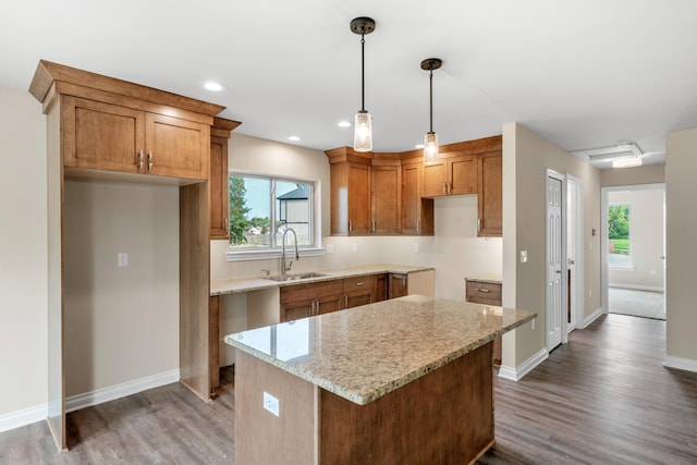 kitchen featuring a kitchen island, dark hardwood / wood-style floors, decorative light fixtures, sink, and light stone counters