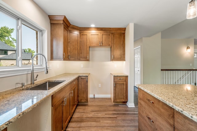 kitchen with light stone counters, sink, decorative light fixtures, and wood-type flooring