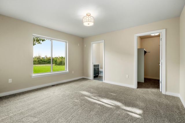 unfurnished bedroom featuring connected bathroom, a spacious closet, and carpet flooring