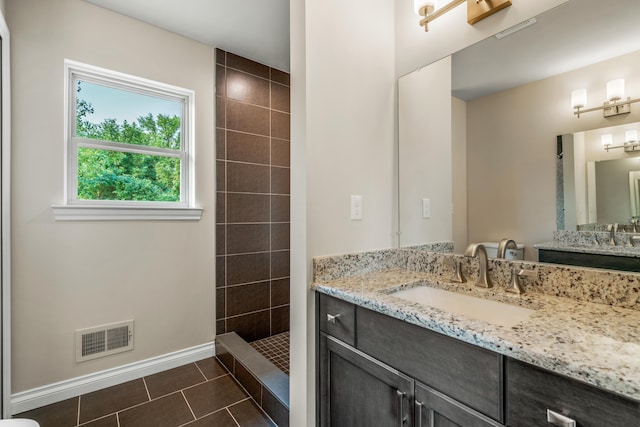 bathroom featuring vanity, tile patterned floors, and a tile shower