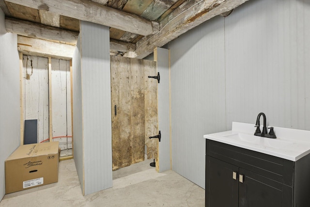 bathroom with vanity, concrete flooring, and wood walls