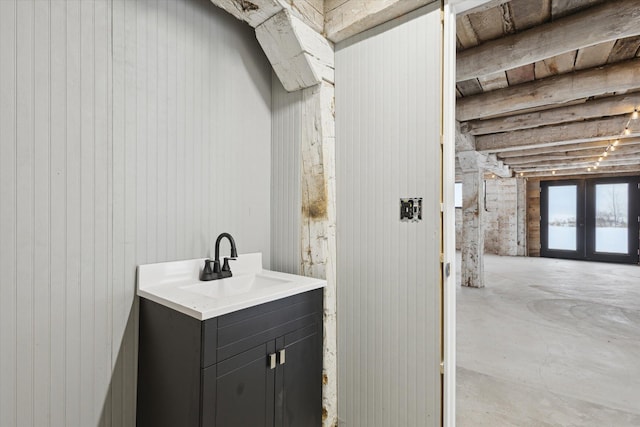 bathroom featuring vanity, concrete floors, wooden walls, and french doors