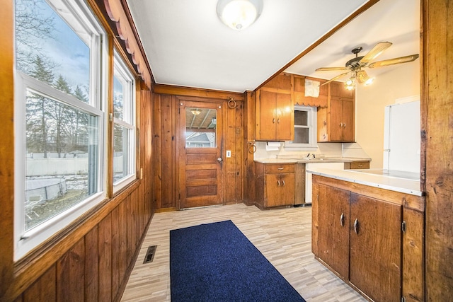 kitchen featuring ceiling fan, wooden walls, light hardwood / wood-style floors, and white fridge