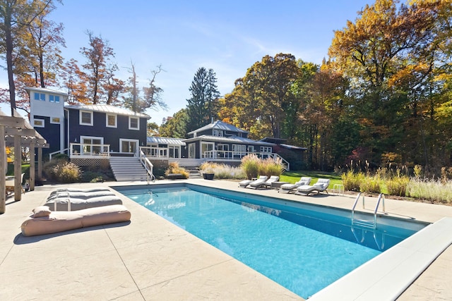 outdoor pool with a patio area and a wooden deck