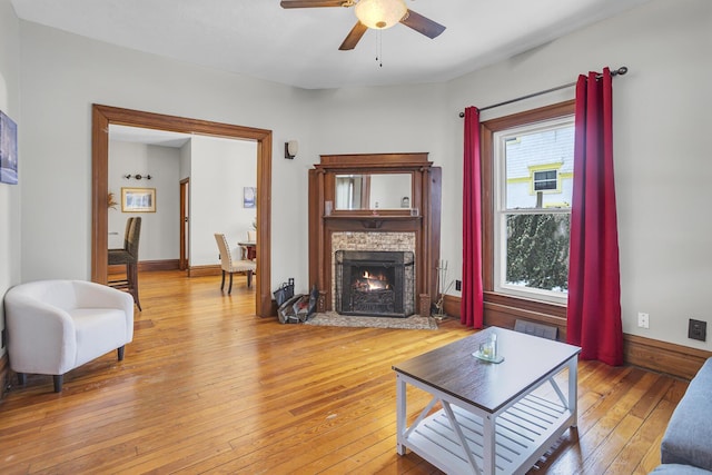 living room featuring ceiling fan, a fireplace, and light hardwood / wood-style floors