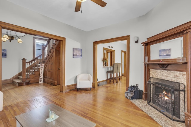 living room featuring hardwood / wood-style floors, a brick fireplace, and ceiling fan