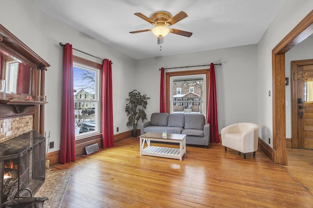 living room featuring ceiling fan, a brick fireplace, and light hardwood / wood-style floors