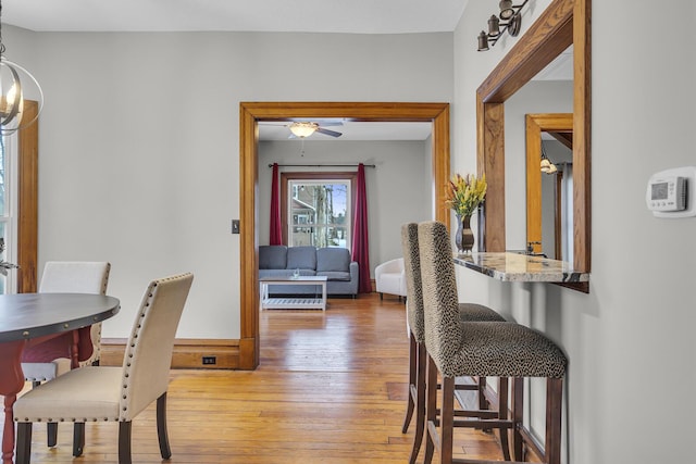 dining area featuring hardwood / wood-style flooring and ceiling fan with notable chandelier