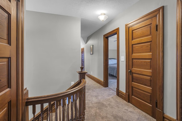 corridor featuring light colored carpet and a textured ceiling