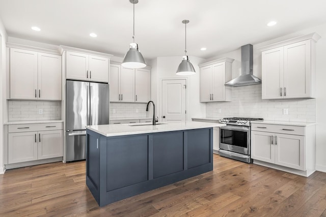 kitchen with stainless steel appliances, hanging light fixtures, wall chimney range hood, and dark hardwood / wood-style flooring