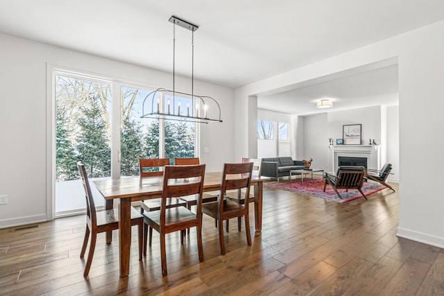 dining area with dark wood-type flooring and an inviting chandelier